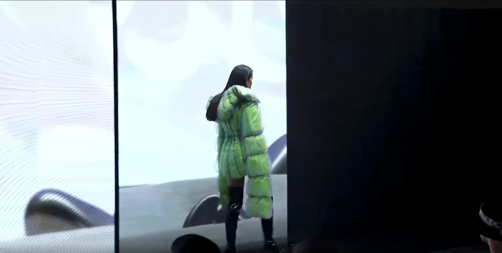 A model walks the Dubai runway in front of a tall LED wall showing the 3D pavilion environment.